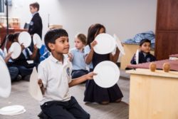 An elementary arts and crafts class using paper plates for an art project