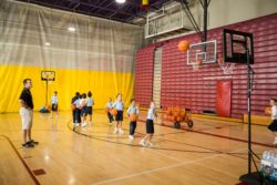 Elementary school children throwing basketballs into hoops to score