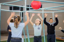 Academy children throw a ball on a playground back and forth