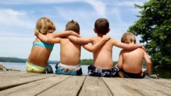 Four young men next to a lake