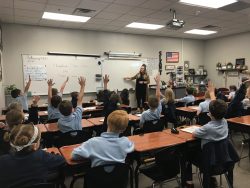 Kids raising their hands in a classroom